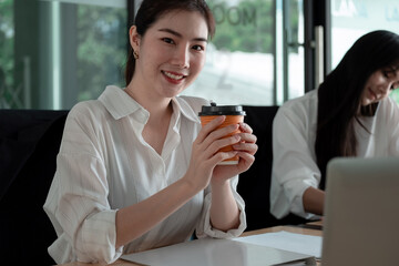 Obraz premium Portrait Of Attractive Asian Businesswoman Working On Laptop for marketing plan, Female hand holding a cujp of coffee