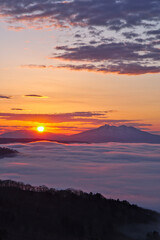 Fototapeta na wymiar 輝く朝陽の下に雲海の広がるドラマチックな夜明け。日本の北海道の美幌峠。