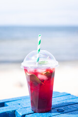 lemonade red soda cherry or strawberry fresh juice, sea coast shore, summer surf wave background refreshing drink relax positive mood vacation top view