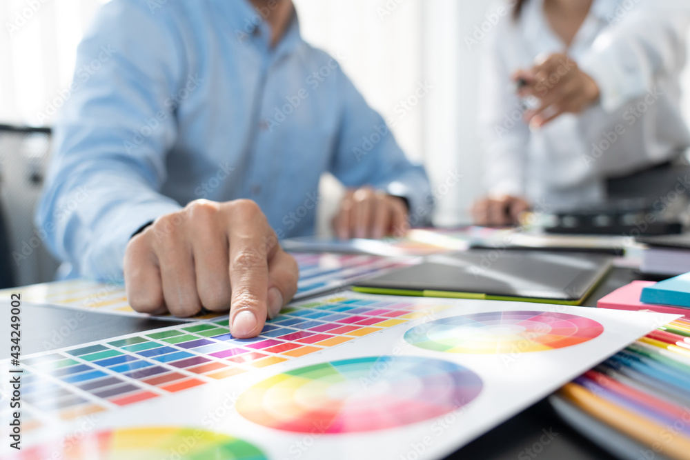 Poster graphic designer team working on web design using color swatches editing artwork using tablet and a 