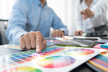 Fototapeta premium graphic designer team working on web design using color swatches editing artwork using tablet and a stylus at desks In creative office