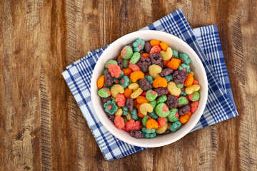 Top view of bowl with fruit cereal naturally and artificially fruit flavored sweetened corn puffs. Cereal fruity shapes