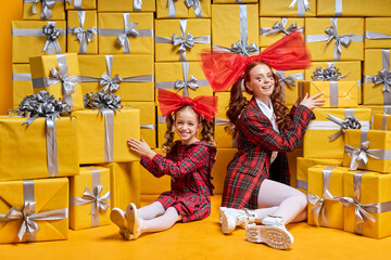 Cute sweet little princess with mother opening present gifts boxes, copyspace. Adorable Pretty woman and kid girl in red party wear dress and bow on head enjoy unpacking