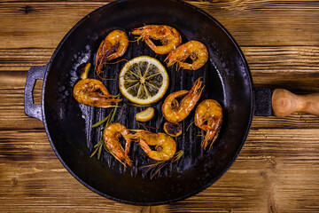 Roasted shrimps with lemon slice, garlic and rosemary in a cast iron pan. Top view