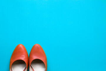 Orange color women shoes on blue color background, with copy space. Job recruitment or hiring concept