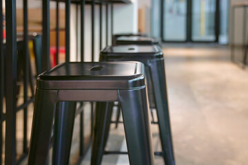 Close up view of black metal stools inside a restaurant. Copy space.