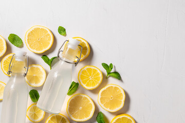 Cold lemon mint lemonade in glass bottles on white background with ingredients. Health care, detox...
