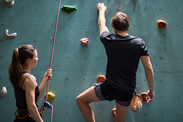 Female instructor giving instructions to man on wall climbing. man learning the art of rock...