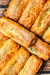 Many cheese and spinach rolls are arranged on a baking tray straight from the oven