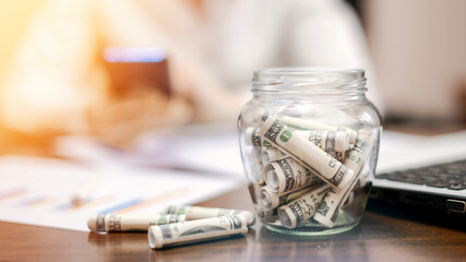 A jar with rolled banknotes on the table