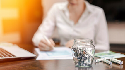 A jar with rolled banknotes on the table