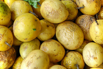 A bunch of organic yellow or golden passionfruit in a market for grocery shopping. Maracuya is rich...