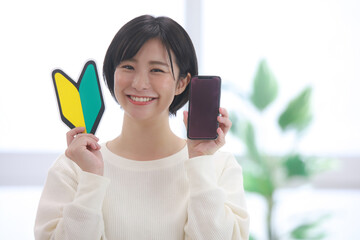 スマートフォンと初心者マークを持つ女性社員