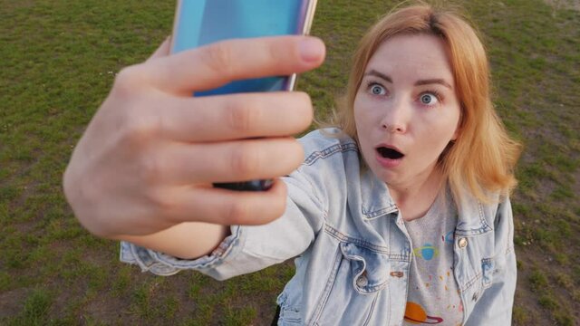 Portrait of shocked young woman who taking video of UFO in the sky 