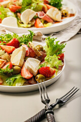 Close-up salad with jamon, strawberries, grapes, mozzarella and olives with pomegranate sauce. Healthy and balanced nutrition. Organic food. Mediterranean cuisine recipes. Vertical shot. Copy space