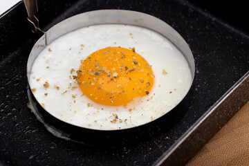 Close-up of sunny side up eggs in a frying pan for breakfast on wooden table background