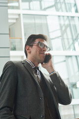 Young businessman in suit talking on mobile phone while standing in the city