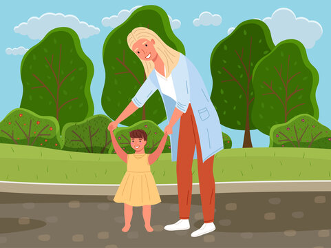 Mother teaches her daughter to walk walk on her own. Baby takes first steps. Family is walking in summer park. Parent spends time with child in nature. Mom holds baby by hands while walking