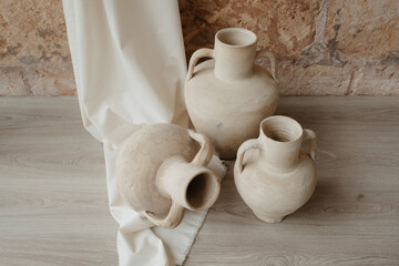 clay jug on wooden table in front of Mediterranean style stone wall
