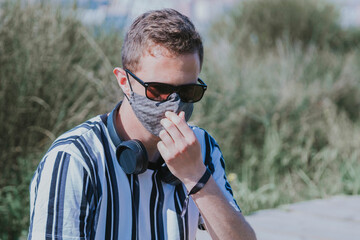 man with medical mask and headphones on the street, concept of leisure in the new normal
