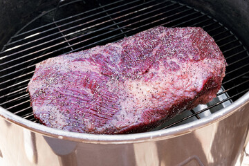 Portion of raw prime marbled beef brisket on a grill