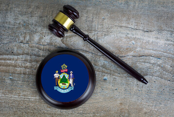 Wooden judgement or auction mallet with of Maine flag. Conceptual image.