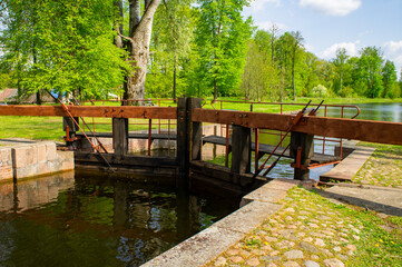 Fototapeta na wymiar Old navigable river sluice. 20th century architecture with wooden mechanics. Augustow Canal, Belarus, 18 May 2021