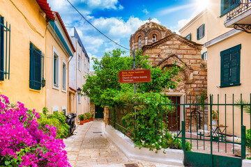 Fototapeta na wymiar The small streets of the old town Plaka of Athens, Greece, with a traditional, orthodox church, colorful houses and blooming bougainvillea