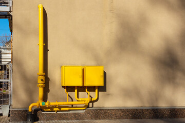 Yellow gas pipes with two closed junction boxes on the wall of the building. Energy supply in an apartment building