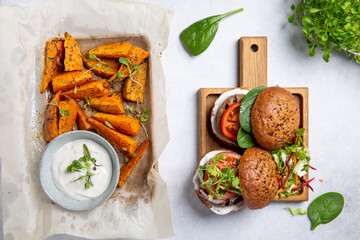 Meat free plant based burger served with sweet potato wedges, green mix salad and white sauce on...