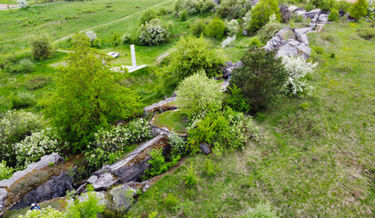 Fototapeta na wymiar A view from a height on a stone rock ruins in a green field. Remains of an old fort of World War II