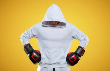 Male trainer posing in the studio with boxing gloves. White hoodie. Mixed martial arts concept.