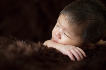 Cute Asian newborn baby on brown fur blanket background.
Nice portrait of little child boy.
