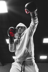Brutal athlete boxing in the ring in a white hoodie covered with a hood. Mixed martial arts concept.