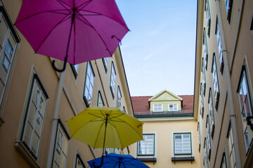 Fototapeta na wymiar Umbrellas with different colors hanging in the Courtyard and public passage Suennhof in the 3rd District in Vienna, Austria 