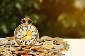 Retro vintage antique pocket watch clock on pile of coins. Money saving or time is money concept..