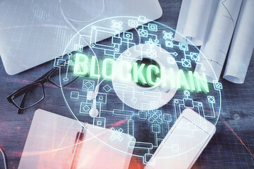 Blockchain theme hologram drawings over computer on the desktop background. Top view. Multi...