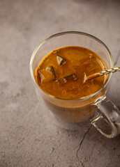 Iced Dalgona coffee drink on wooden tray background. Instant coffee or espresso powder whipped with sugar and hot water. Coffee with milk latte, cappuccino. Two glass cups with double walls. Breakfast