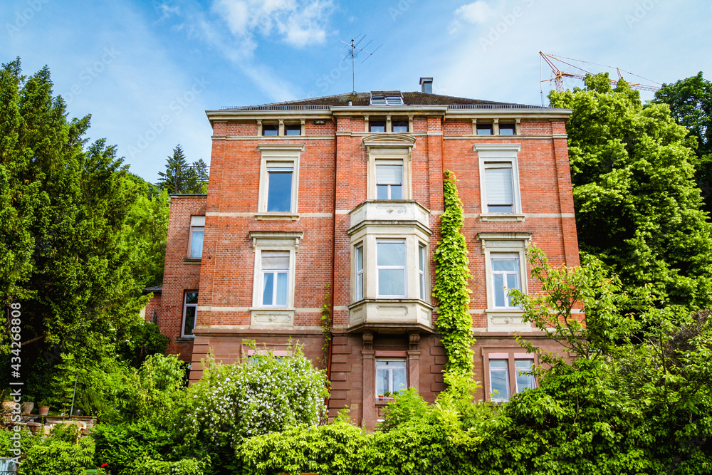 Wall mural A beautiful brick villa surrounded by trees and bushes.