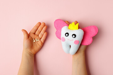 Felt tooth fairy pillow and milk tooth in kids hands on pink background with copy space for text. Handmade children's felt tooth fairy pillow. Stuffed toy crafts idea. Happy Tooth Fairy day card