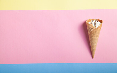  Ice cream in waffle cone on yellow, blue, pink background.