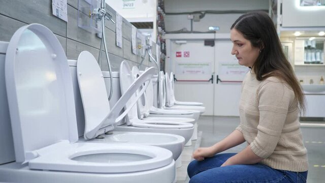Woman chooses toilet bowl with seat lift.