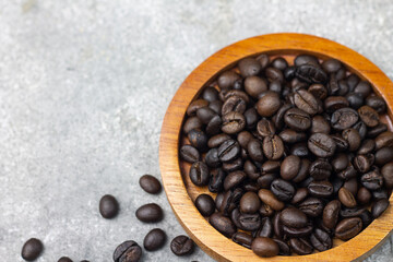 Biji Kopi or Coffee beans on wooden plate and coffee beans on grey background. Close up view. Copy space for text. 