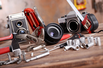 Analoge TLR und SLR Fotokameras mit unterschiedlichen Werkzeugen auf Holztisch vor Vintage...