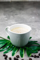 A Cup of hot Cappuccino coffee on wooden tray, with cofee beans on grey background. Selective focus, copy space.