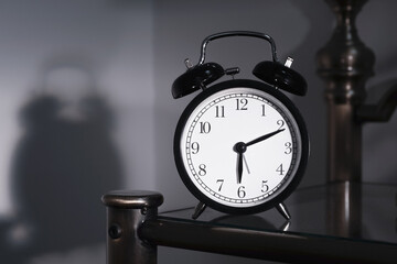 Black white alarm clock on the bedside table. Selective focus