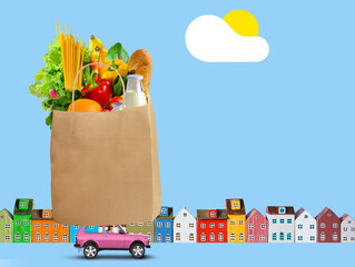 Pink car with shopping paper bag with groceries on the roof on city background