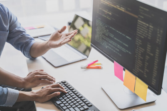 Programming developing software application. programmer writing program code with two monitors and working hacker on a new software
