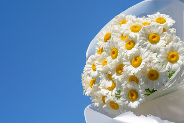 large bouquet of daisies on a blue sky background, copy space