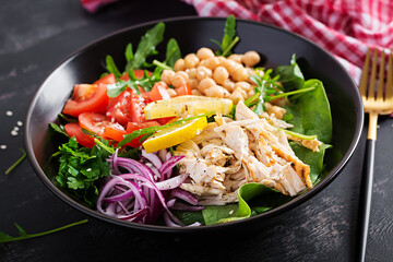 Buddha bowl dish with chicken fillet, chickpeas, tomatoes, red onion, fresh green salad and seed sesame. Healthy balanced eating.